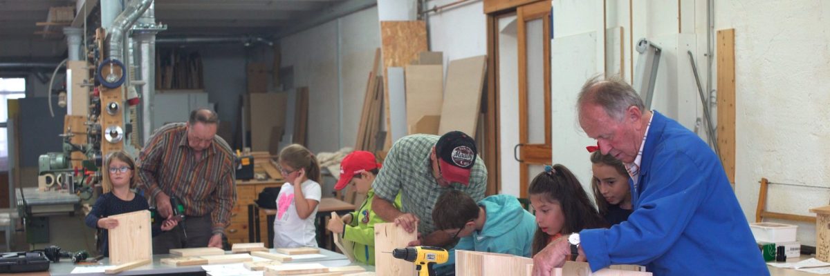 Dieses Bild zeigt Erwachsenen und Kinder bei der Errichtung eines Vogelhauses.
