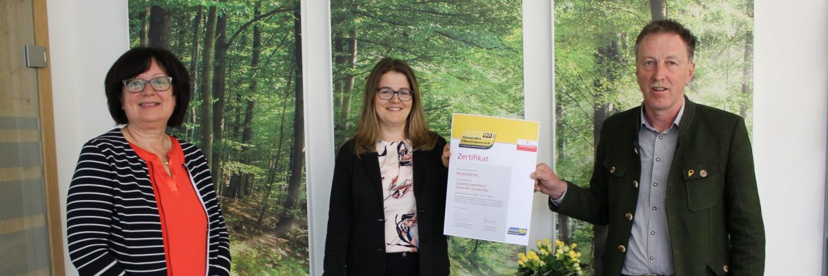 Dieses Bild zeigt v.l.n.r. Mitarbeiterin Adelheid Schicktanz, Arbeitskreisleiterin Verena Aigner und Bürgermeister Martin Voggenberger mit dem Qualitätszertifikat der Gesunden Gemeinde.