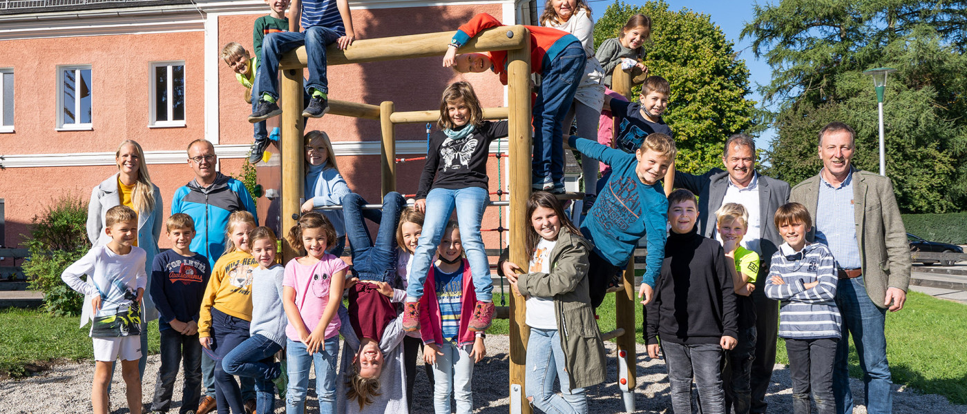 Dieses Bild zeigt die Schülerinnen und Schüler der Volksschule Munderfing bei der Übergabe des Klettersechsecks gemeinsam mit (v.l.n.r.) Amtsleiterin Rebekka Krieger, Andreas Permatinger-Kraus (AMAG Projektpate), Leopold Pöcksteiner (AMAG) und Bürgermeister Martin Voggenberger. (Foto: AMAG)