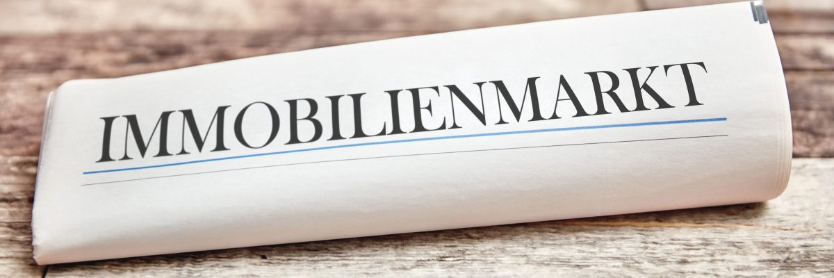 Dieses Bild Zeigt eine zusammengerollte Zeitung mit dem Text Immobilien