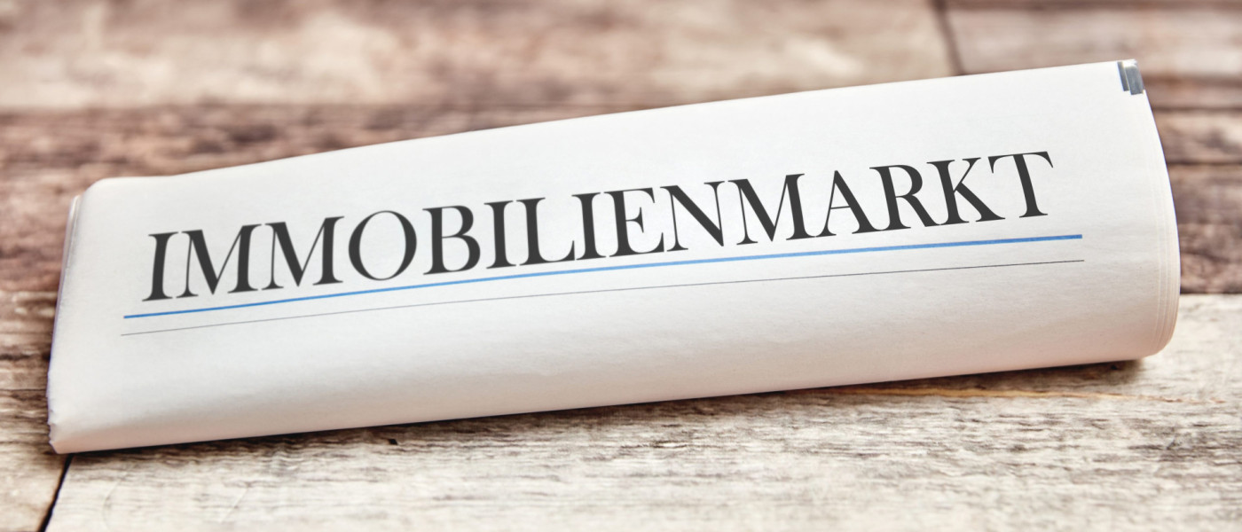 Dieses Bild Zeigt eine zusammengerollte Zeitung mit dem Text Immobilien