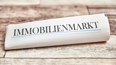 Dieses Bild Zeigt eine zusammengerollte Zeitung mit dem Text Immobilien