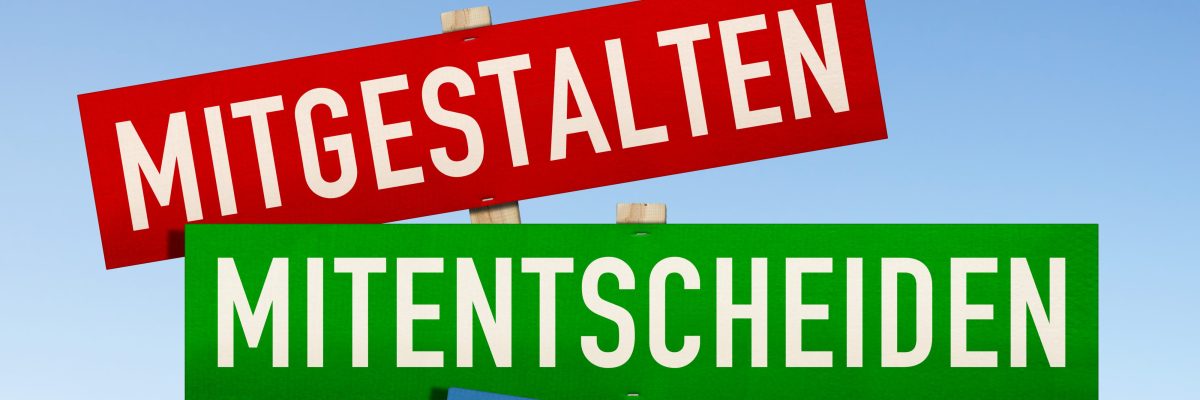 Dieses Bild zeigt den Schriftzug Mitgestalten, Mitentscheiden und Mitdenken auf einem roten, grünen und blauen Schild