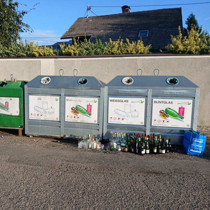 Glascontainer mit verschiedenen Glasflaschen davor in Österreich
